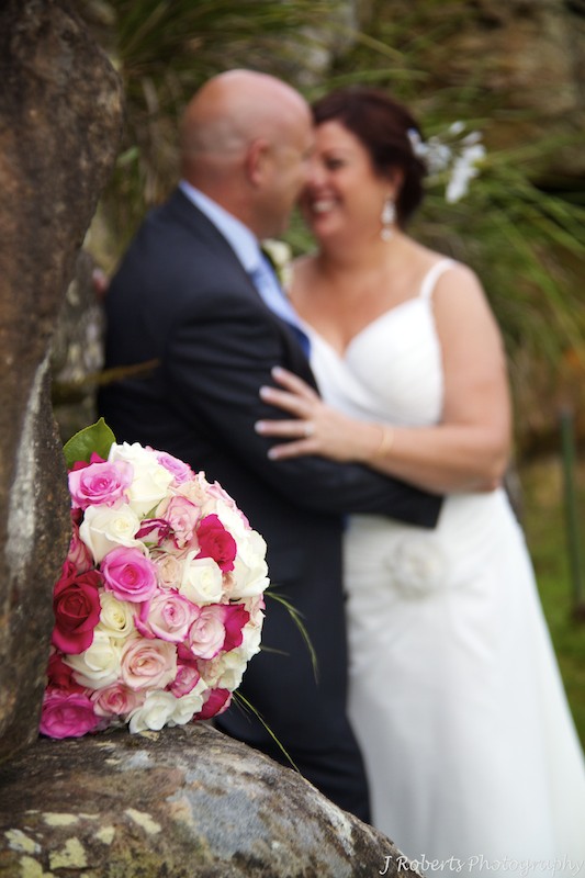 Bridal bouquet with couple behind by Show Posies - wedding photography sydney